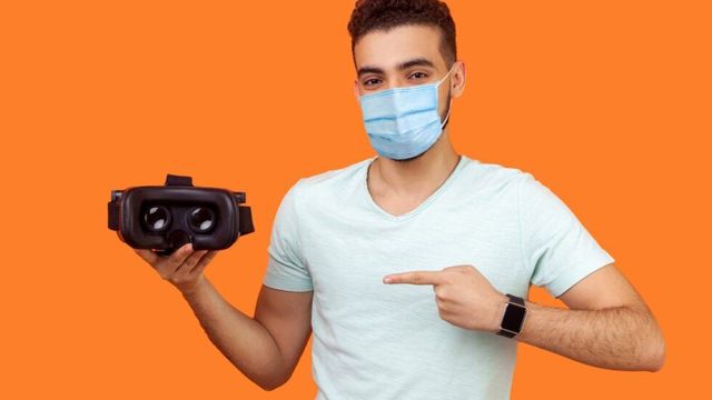 マスクを着けた男性がVRヘッドセットを紹介している様子