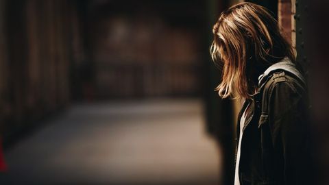 Une femme seule, tête baissée, dans une pièce sombre