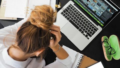 デスクでパソコンを前にストレスを感じている女子学生