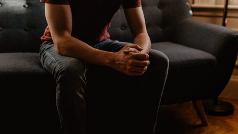 Une personne assise, mains jointes, dans une posture préoccupée