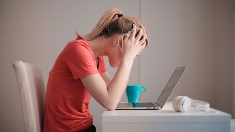 パソコンの前で頭を抱える、ストレスを感じた女性