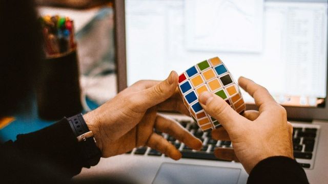 パソコンの前でルービックキューブを操作する人