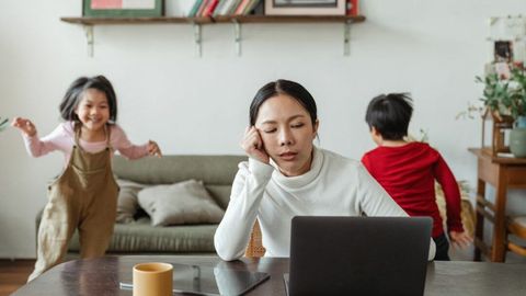子どもたちが遊ぶそばで仕事をする、余裕のない母親