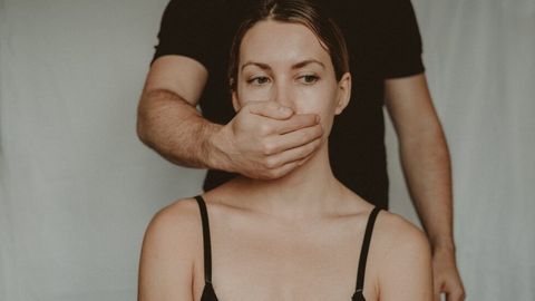 女性の口を覆う手