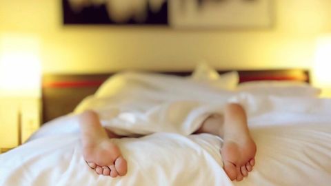 掛け布団の下に横たわる、足だけが見える二人