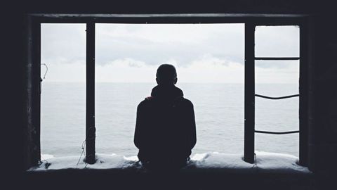 Silhouette d’une personne seule devant une grande fenêtre