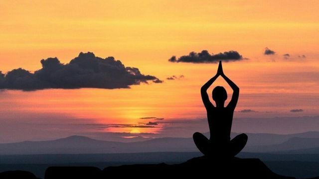 夕日を前に瞑想する人のシルエット