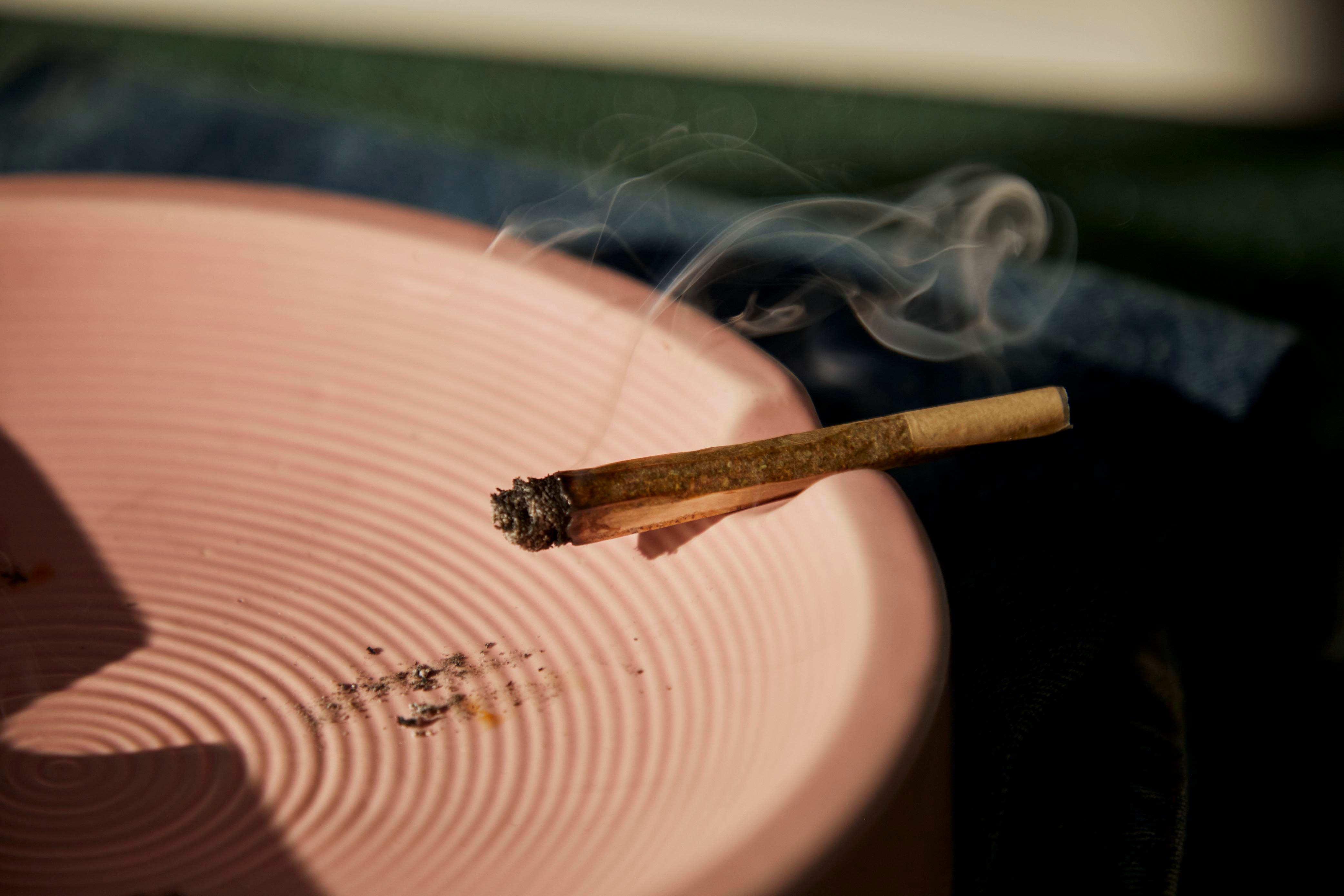 Cigarette au CBD fumante posée sur un cendrier