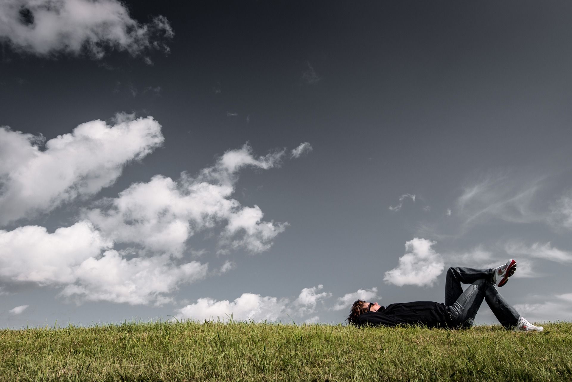 Une personne allongée dans l’herbe regarde les nuages