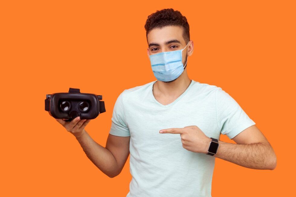 Un hombre con mascarilla presenta un casco de realidad virtual
