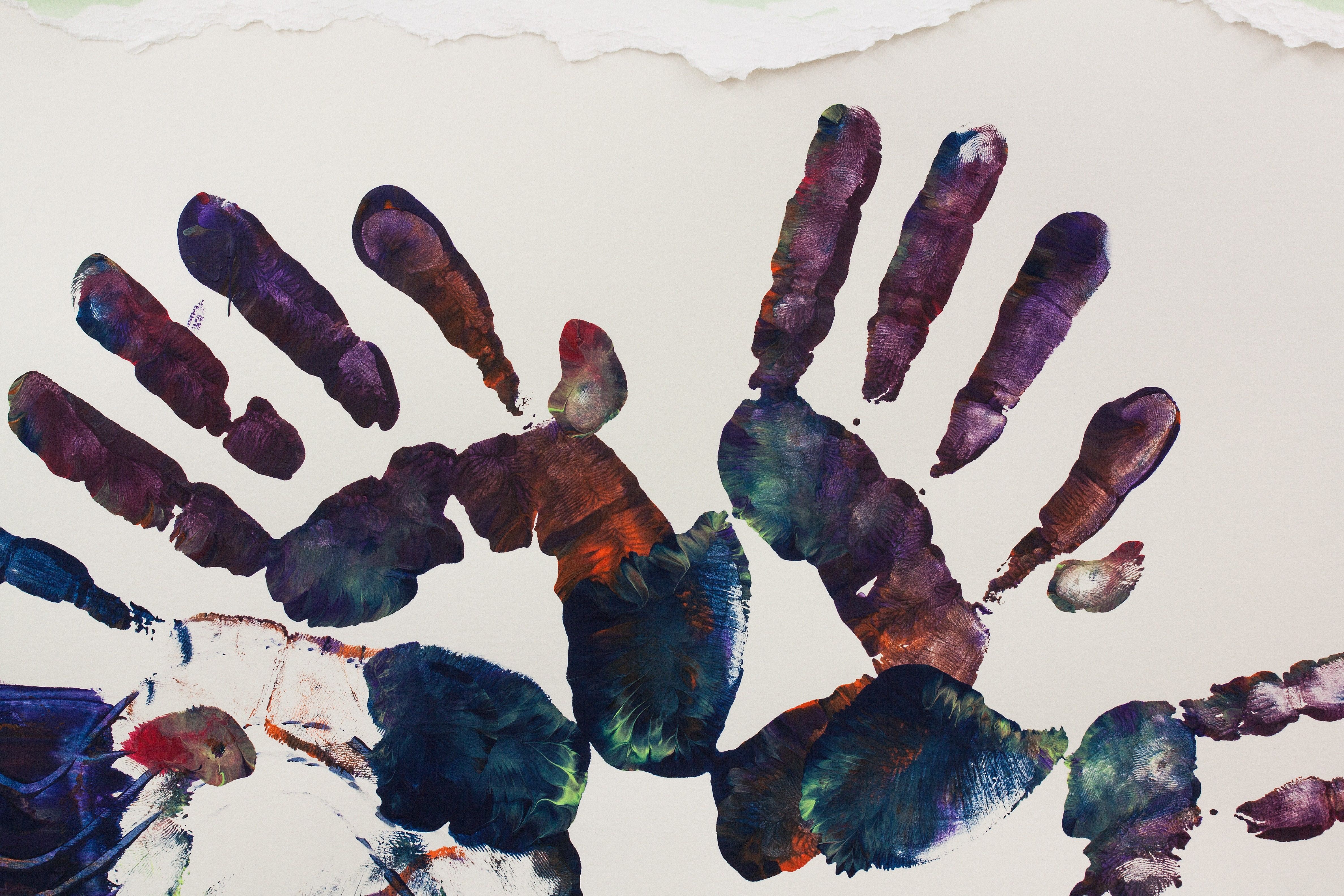 Empreintes de mains en peinture multicolore sur du papier blanc