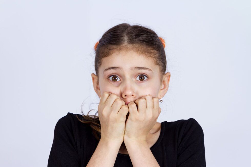 Una niña ansiosa se muerde las uñas