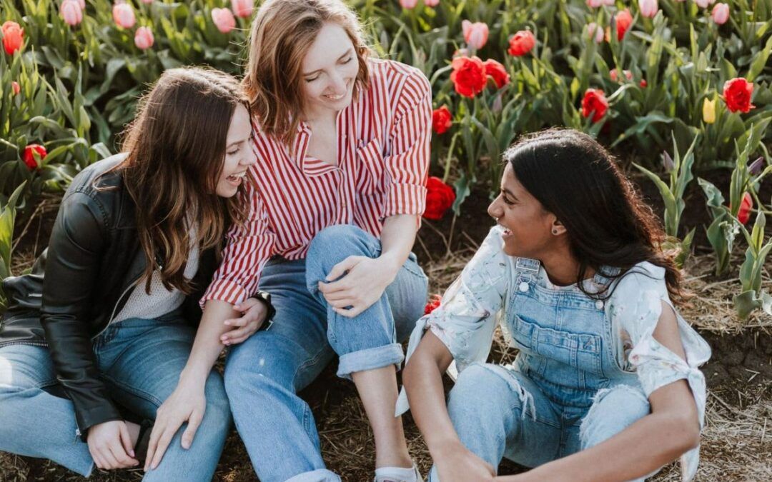 Tres jóvenes conversan en un jardín florido