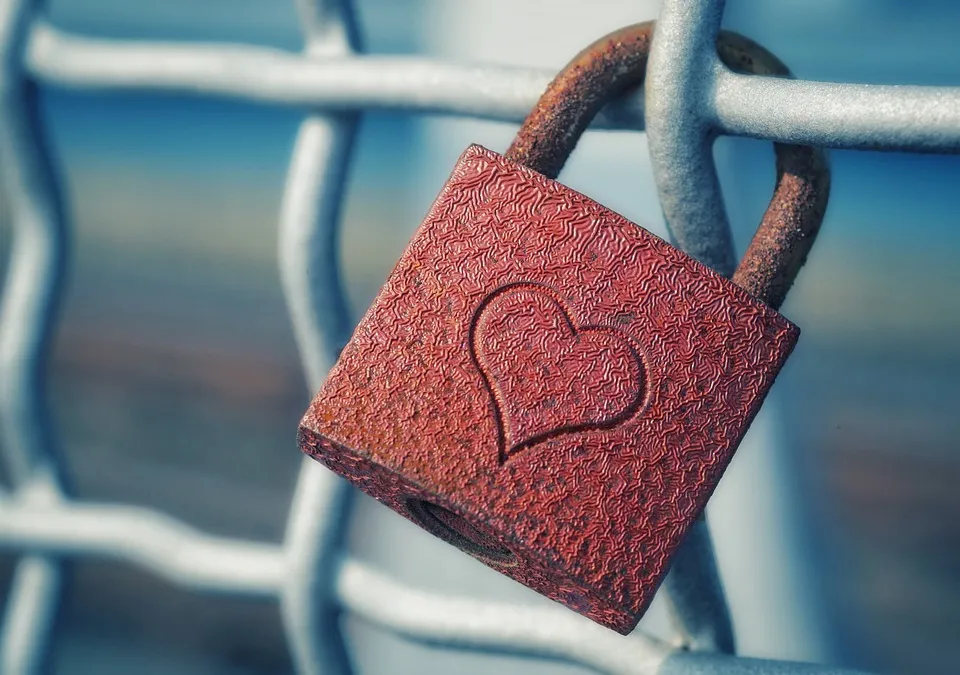 Candado rojo con un corazón sujeto a una reja