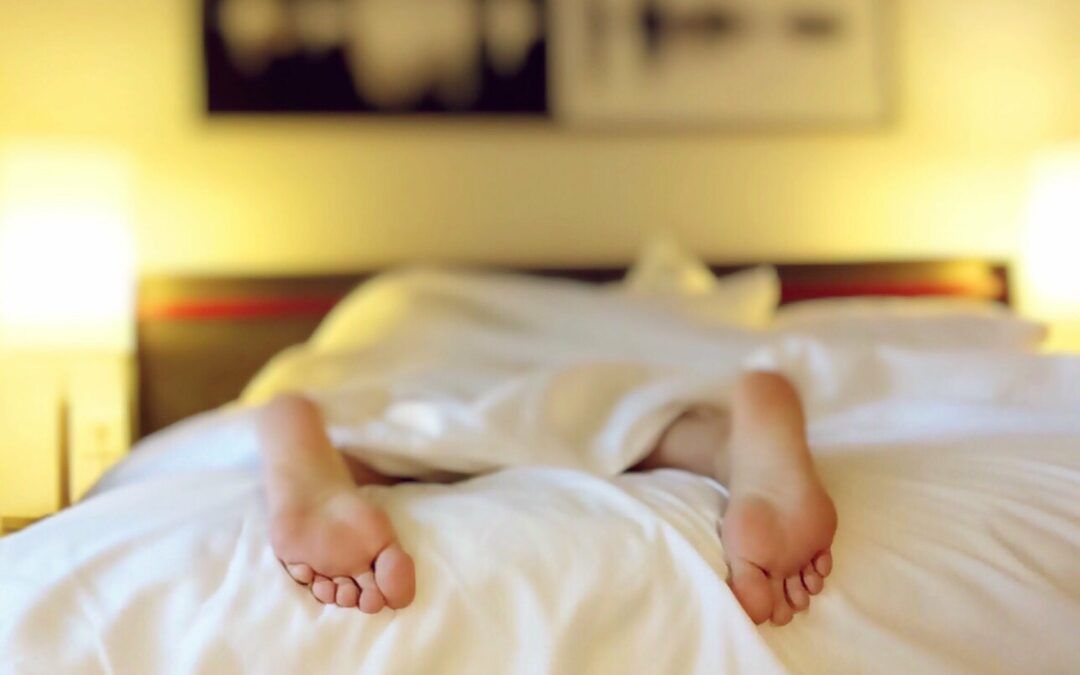 Dos personas tumbadas bajo un edredón con los pies visibles