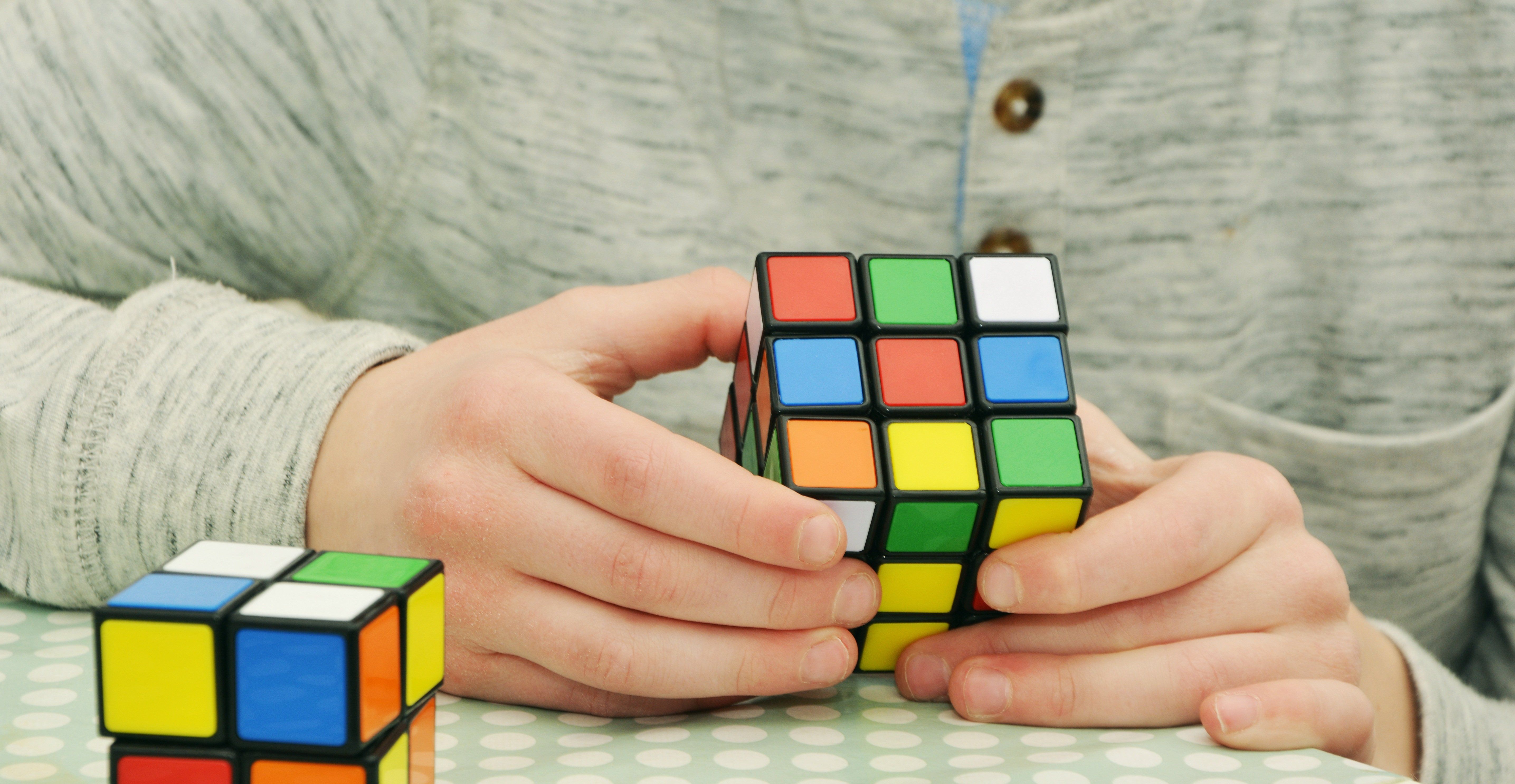 Une personne manipule un Rubik’s Cube, avec un second cube posé sur la table