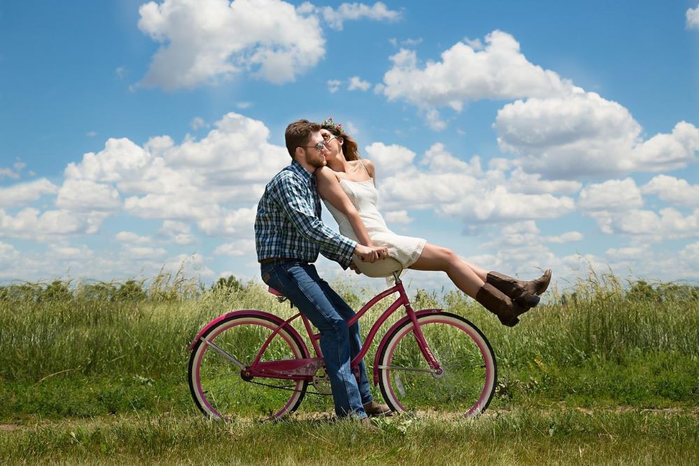 Ein Paar küsst sich auf einem Fahrrad in einem Feld