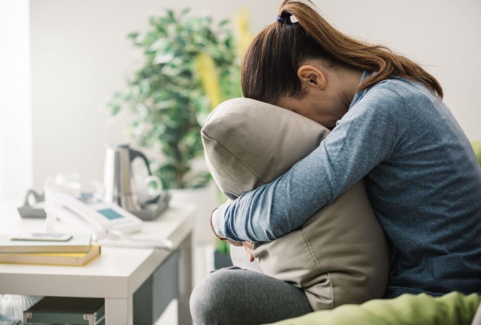 Una mujer acurrucada abraza un cojín