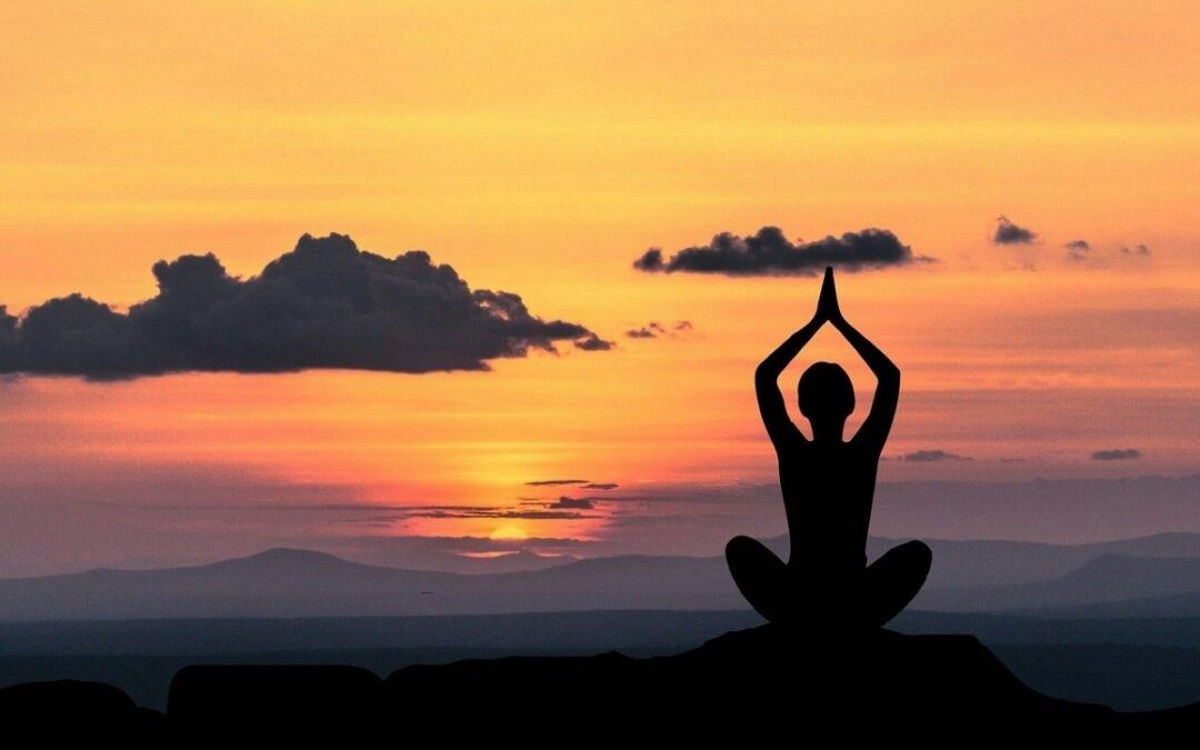 Silueta meditando frente a una puesta de sol